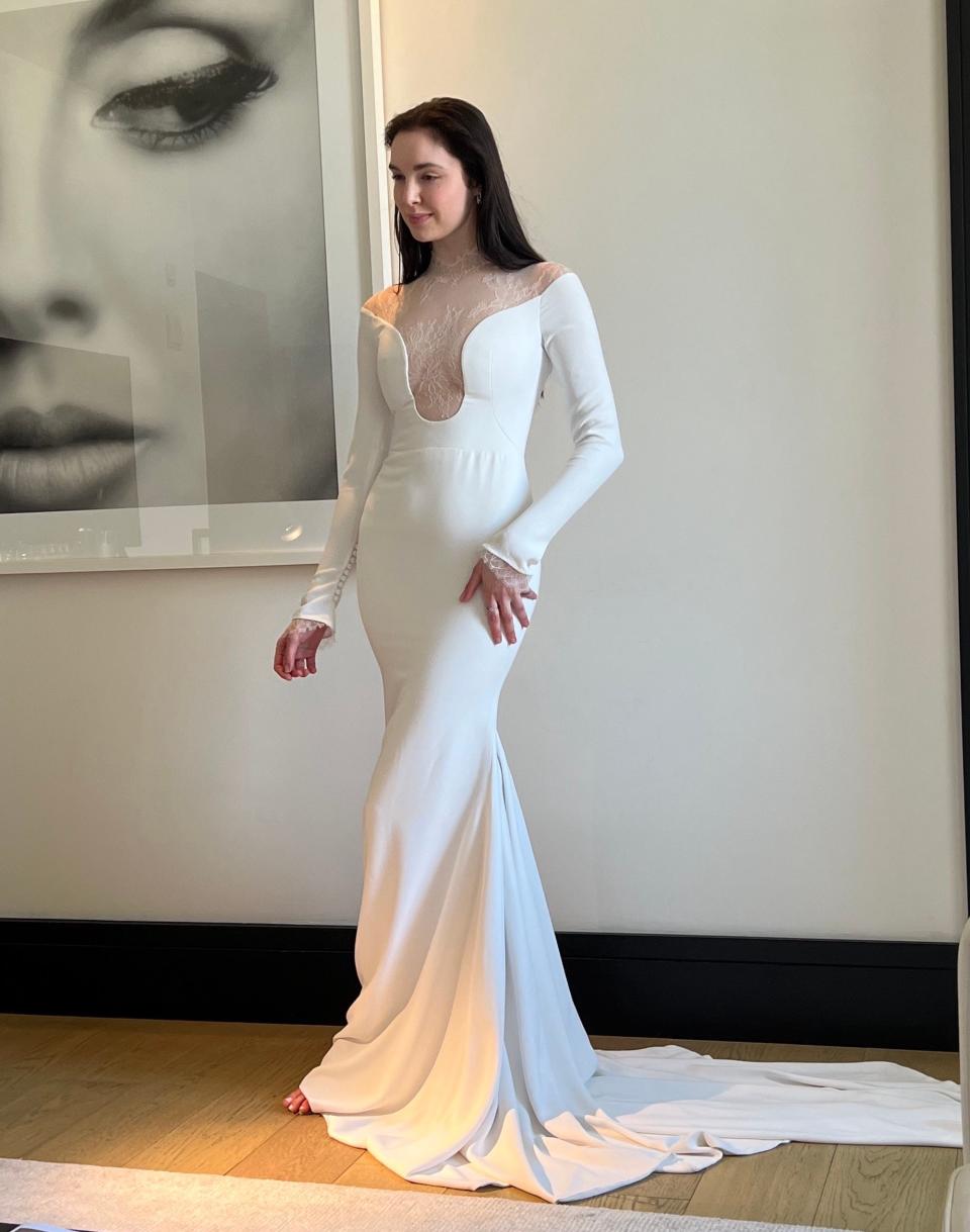 A woman poses in a wedding dress with a bodysuit under it.