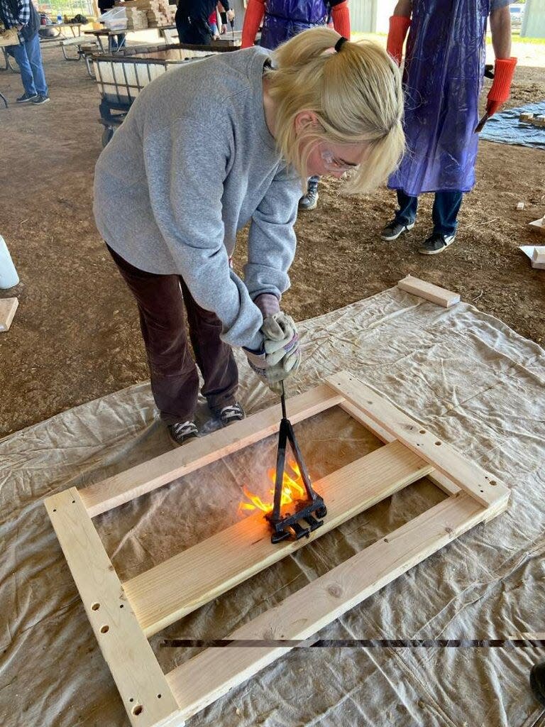 Lana Tuey of Thompson’s Station who is, along with her parents, part of the leadership and core nonprofit team, brands the SHP logo into a bed frame, while volunteering at Maury County Park on April  29, 2023 in Columbia.