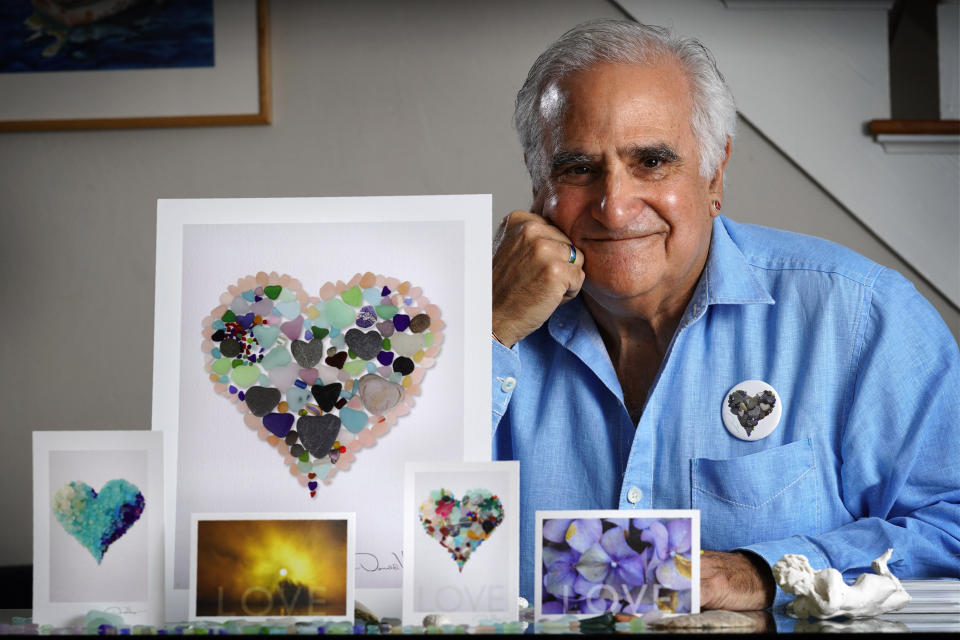 Artist Donald Verger poses with his images of sea glass, landscapes and flowers, Thursday, Feb. 11, 2021, in Falmouth, Maine. Verger, who has donated his photography to schools and hospitals, said he considers his small but colorful contribution a way of bringing a smile to people's faces during the ongoing pandemic. (AP Photo/Robert F. Bukaty)