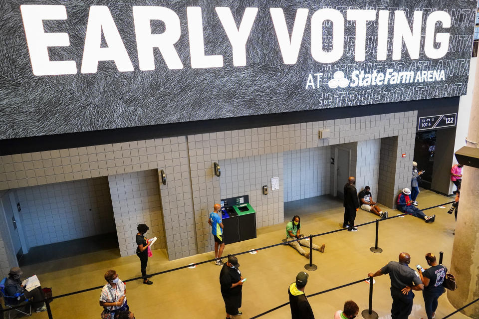 FILE - In this Oct. 12, 2020, file photo, people wait in line to vote early at the State Farm Arena in Atlanta. A surge in coronavirus cases is hitting key presidential battleground states a little more than two weeks before the November election. Voters in Georgia, Texas and elsewhere encountered hours-long lines that required congregating with hundreds of other people. (AP Photo/Brynn Anderson, File)