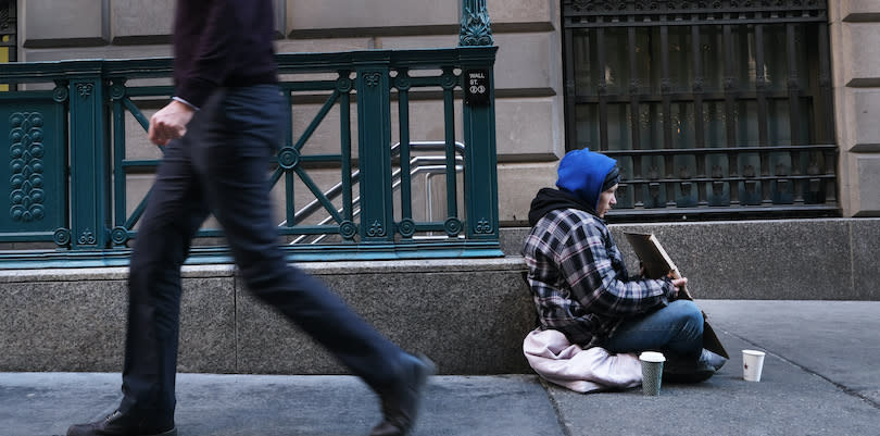 A homeless person sits on the curb in New York City