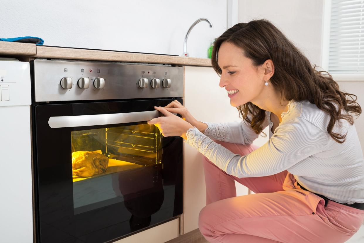 woman roasting chicken meat in kitchen oven