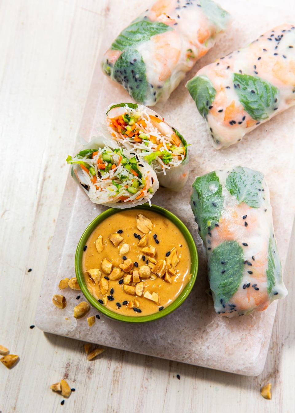 summer rolls and a bowl of peanut sauce on a marble platter