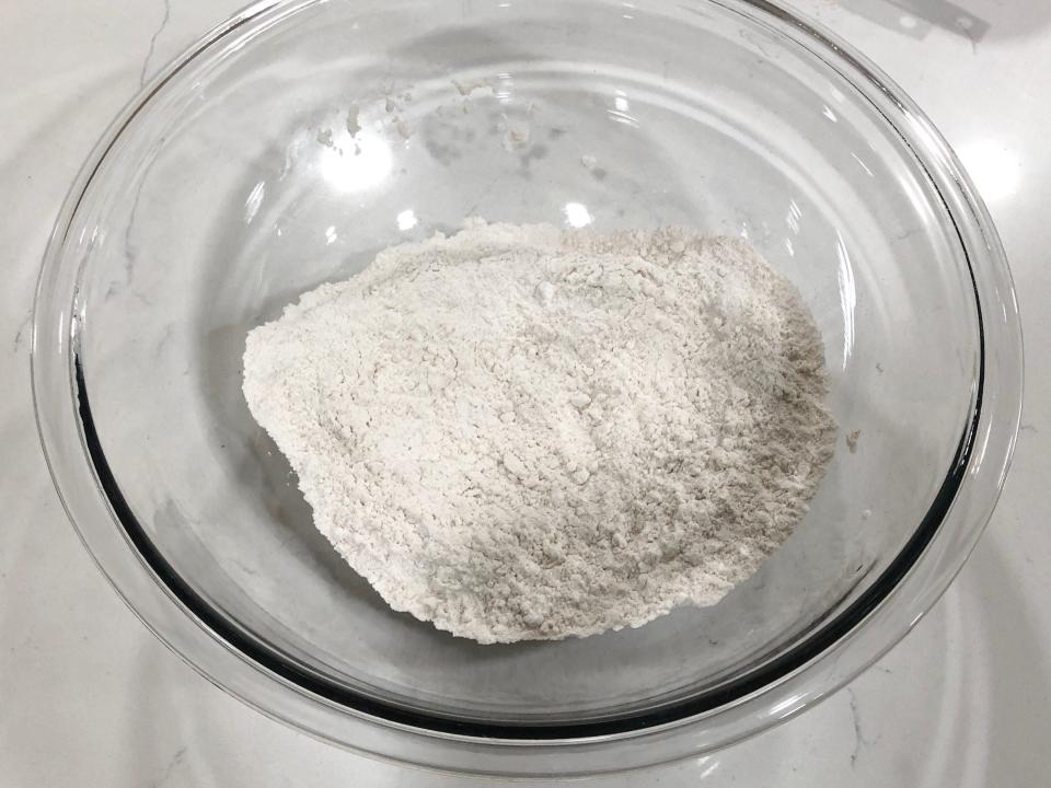 Flour, baking powder, and salt in a clear bowl on a white counter.