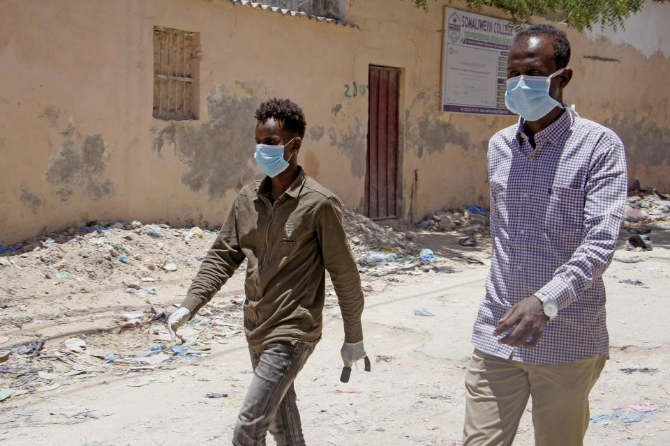 Somali men wear surgical masks on the street after after the government announced the closure of schools and universities and banned large gatherings, following the announcement on Monday of the country's first case of the new coronavirus, in the capital Mogadishu, Somalia Wednesday, March 18, 2020. For most people, the new coronavirus causes only mild or moderate symptoms such as fever and cough and the vast majority recover in 2-6 weeks but for some, especially older adults and people with existing health issues, the virus that causes COVID-19 can result in more severe illness, including pneumonia. (AP Photo/Farah Abdi Warsameh)