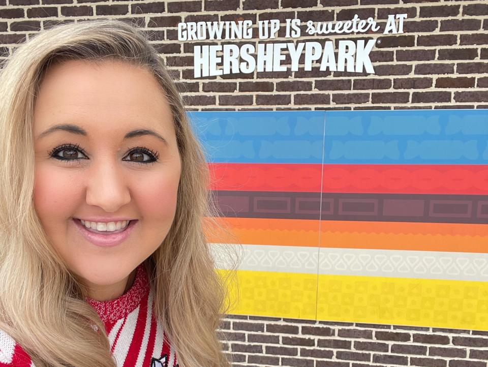 carly posing for a selfie in front of a hersheypark sign at the theme park