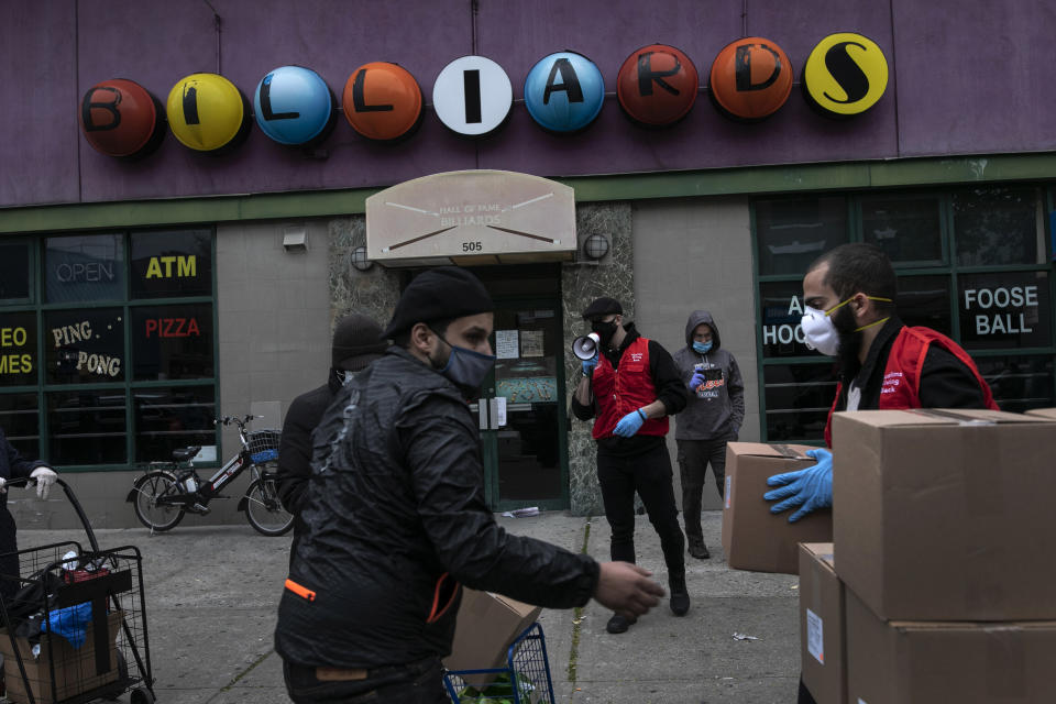 Ahmad Soliman, 33, left, a volunteer with Muslims Giving Back, hands out boxes of food to needy families in the Bay Ridge neighborhood of Brooklyn in New York, on Wednesday, April 29, 2020. (AP Photo/Wong Maye-E)