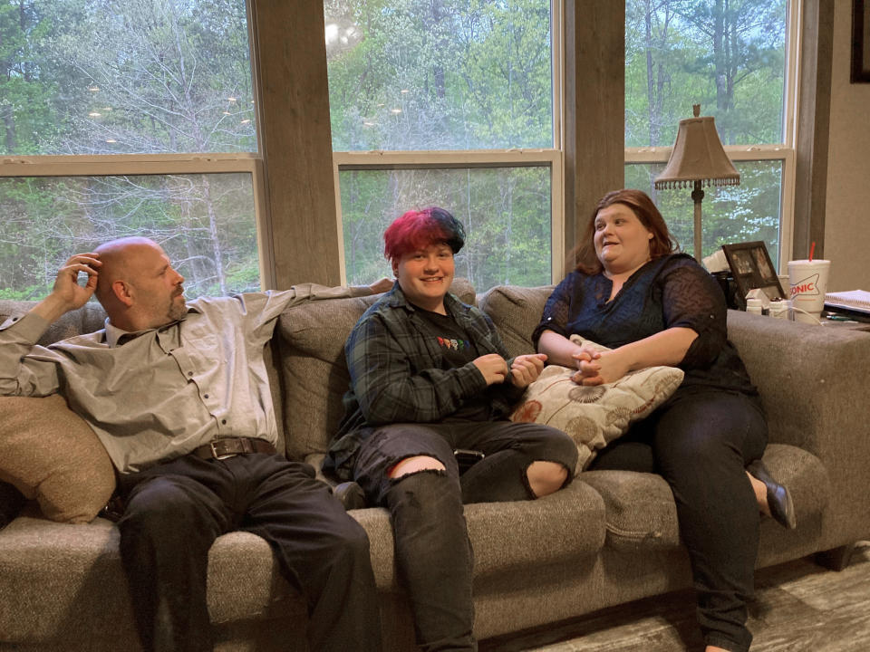 FILE - In this April 15, 2021 file photo, Andrew Bostad, center, talks with his mother, Brandi Evans and stepdad Jimmy Evans at their home in Bauxite, Ark. Andrew is one of hundreds of transgender youth in Arkansas who could have their hormone therapy cut off under a new state law banning gender confirming treatments for minors. A federal judge on Wednesday, July 21, has temporarily blocked Arkansas' ban on gender confirming treatments for transgender youth while a lawsuit challenging the prohibition proceeds. (AP Photo/Andrew DeMillo, File)