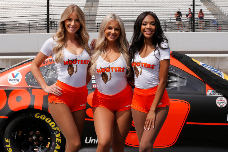 Hooters waitresses posing in front of a race car.