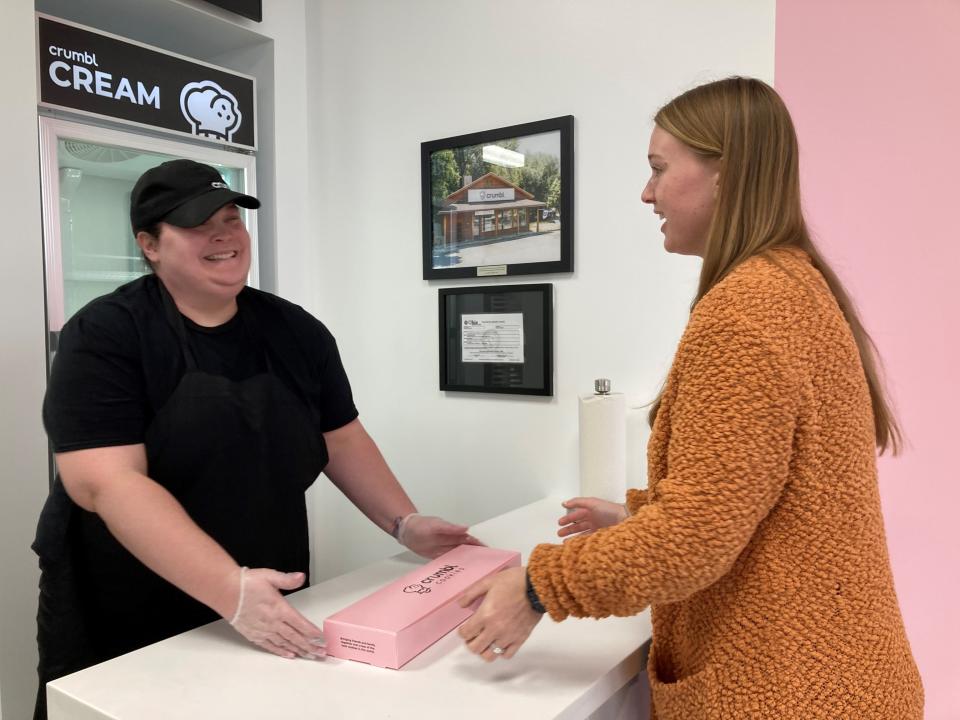 Crumbl Cookies employee Alicia Acord, left, hands a box of cookies to Katelyn McCann, right, on Thursday, Feb. 16. Crumbl, a national bakery chain, opened a location in Heath's Cross Creek Shopping Center.