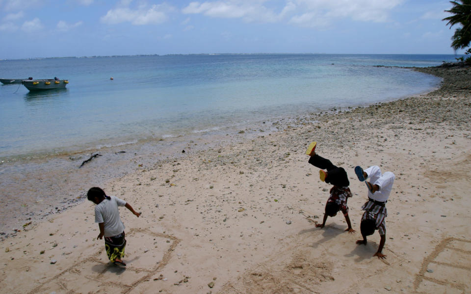 Bikinian children play on the beach of Ejit island, after Palm Sunday church service, in the Marshall Islands, April 4, 2004. (AP Photo/Richard Vogel)