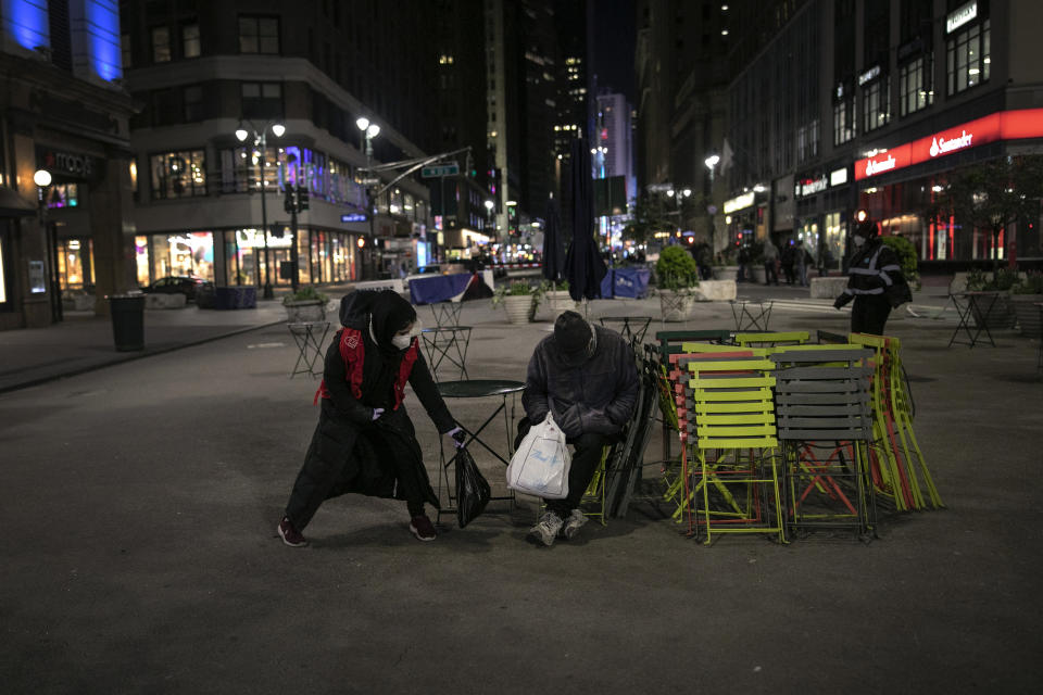 Dania Darwish, 27, director of the Asiyah Women's Center and a volunteer with Muslims Giving Back, places a packet of warm food beside a homeless man, in Herald Square, New York, on Tuesday, April 28, 2020. Some of the food comes from donors like Hamza Deib, the 28-year-old owner of Brooklyn's Taheni Mediterranean Grill. The halal food he donates is the same that he serves in his restaurant -- on one night, rice, chicken, mixed vegetables and falafel for vegetarians. (AP Photo/Wong Maye-E)