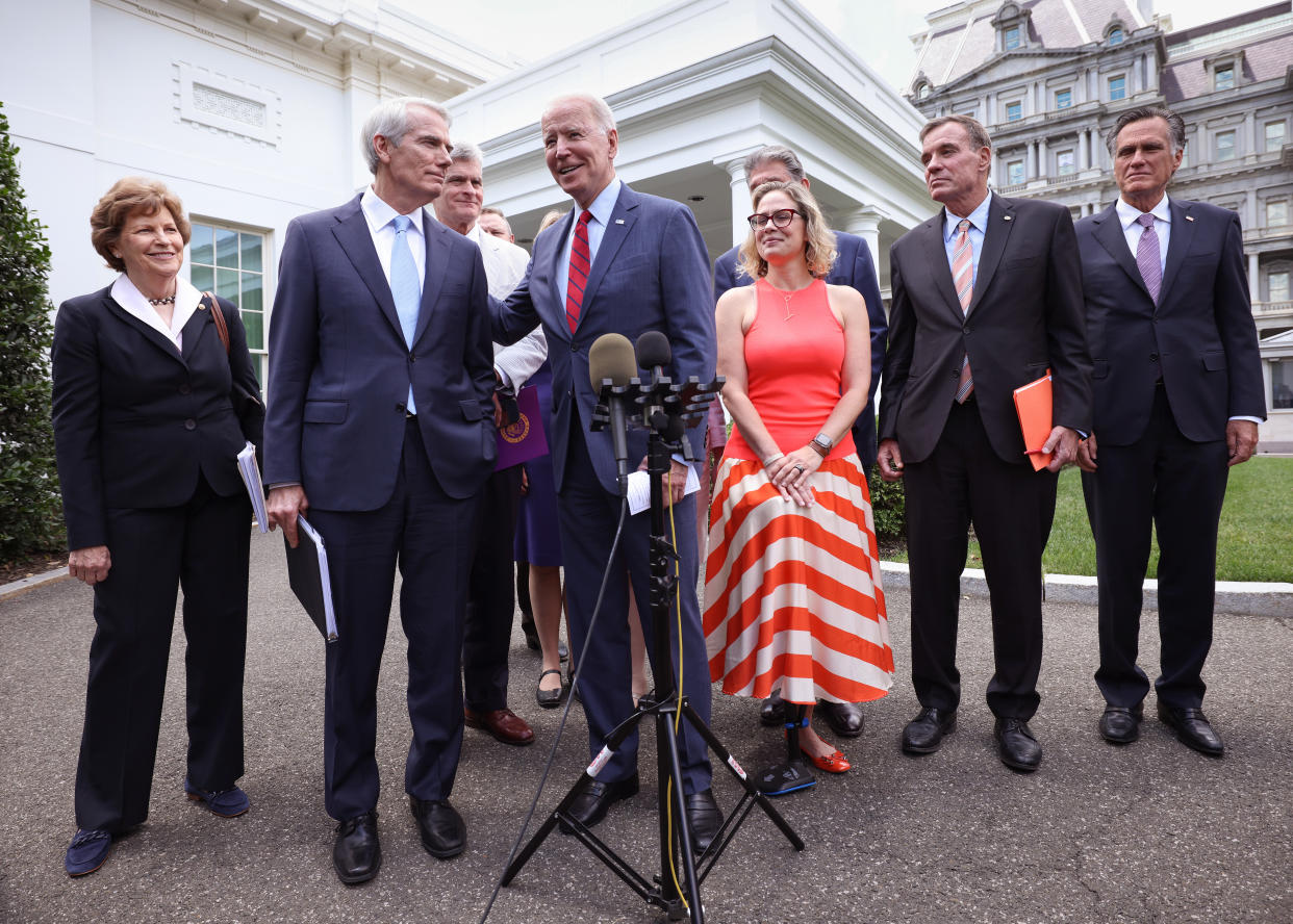 President Joe Biden (C), joined by from left to right, Sen Jeanne Shaheen (D-NH), Sen. Rob Portman (R-OH), Sen Bill Cassidy (R-LA), Sen. Kyrsten Sinema (D-AZ), Sen. Mark Warner (D-VA) and Sen Mitt Romney (R-UT), speaks after the bipartisan group of Senators reached a deal on an infrastructure package at the White House on June 24, 2021 in Washington, DC.  (Kevin Dietsch/Getty Images)