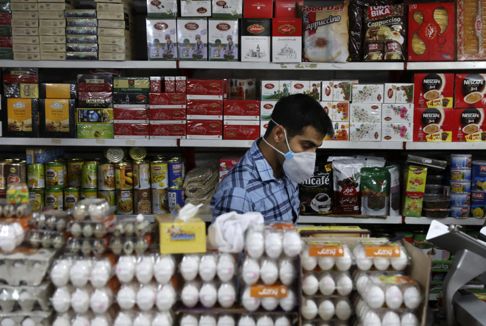 Shopkeeper Tohid Vatanparast, wearing a protective face mask to help prevent the spread of the coronavirus, works at his grocery in Tehran, Iran, Tuesday, April 21, 2020. Iran is the region's epicenter of the COVID-19 pandemic, though even Iran's parliament suggests the death toll is nearly double that and overall cases remain vastly underreported. (AP Photo/Vahid Salemi)