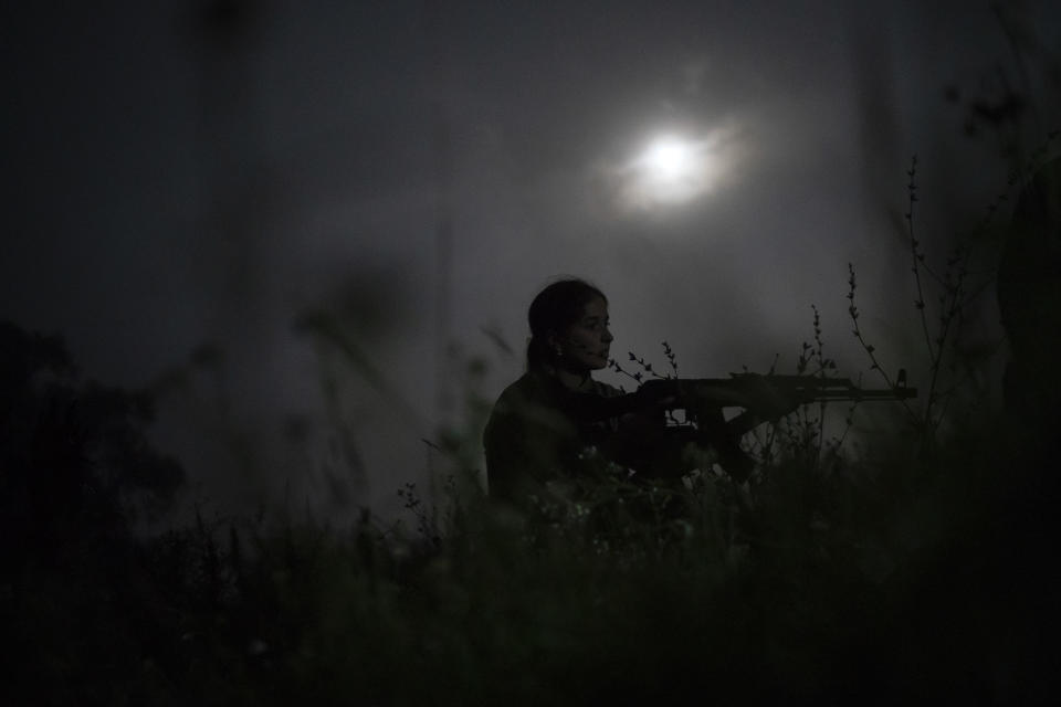 In this July 29, 2018 photo, a young participant of the "Temper of will" summer camp, organized by the nationalist Svoboda party, takes position with her unloaded AK-47 riffle during a night exercise in a village near Ternopil, Ukraine. (AP Photo/Felipe Dana)