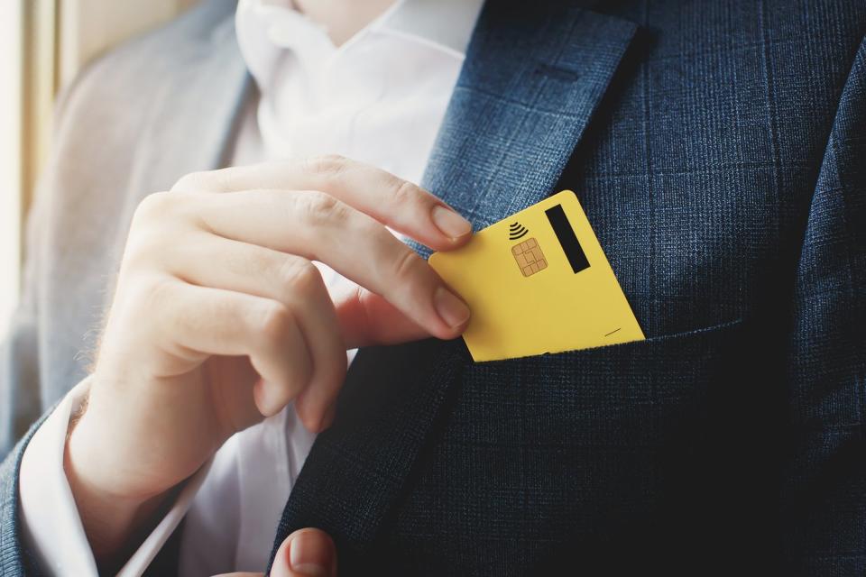 Person pulling credit card out of suit pocket.