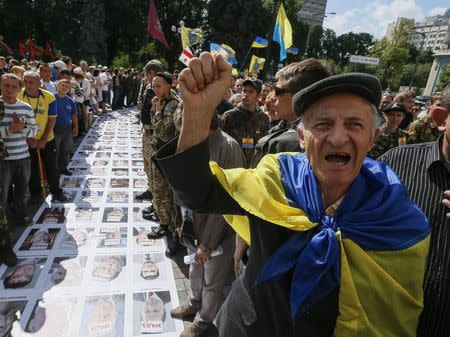 People protest near a "corridor of shame" made up of portraits of Ukrainian deputies from the Party of Regions and Communist Party laid out on the ground to press demands for parliament to be dissolved and early elections outside the assembly at the entrance to parliament in Kiev June 17, 2014. REUTERS/Gleb Garanich