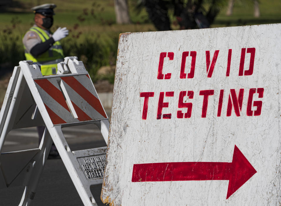 A COVID testing sign directs drivers waiting in line to get a free COVID-19 self-test at Dodger Stadium in Los Angeles, Tuesday, Dec. 1, 2020. California has asked hospitals to ramp up their coronavirus testing amid a surge of new cases, urging them to test health care workers at least once per week while testing all new patients before admitting them. (AP Photo/Damian Dovarganes)