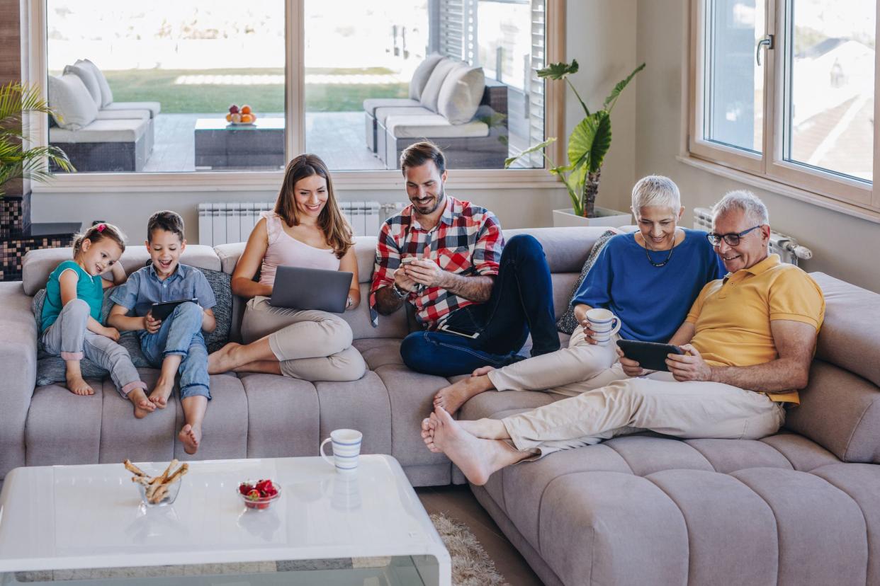 Happy extended family relaxing on the sofa at home and using wireless technology.
