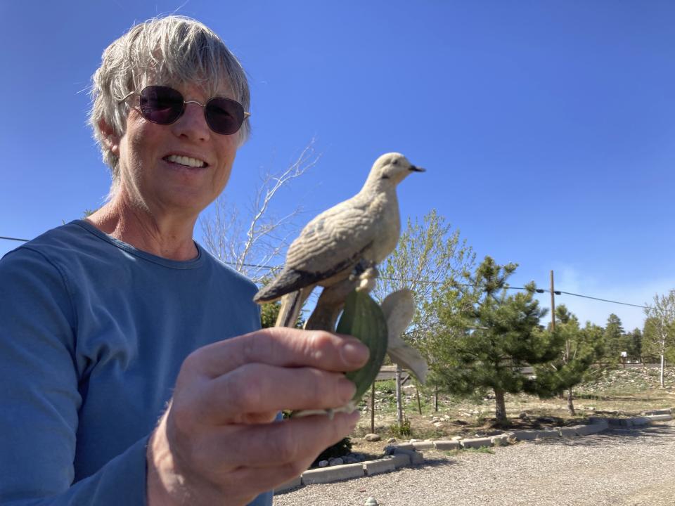 Lisa Wells holds a porcelain dove on Wednesday, April 20, 2022, that her son-in-law recovered from the ashes of her home that was destroyed by a wildfire on the outskirts of Flagstaff, Ariz. The wildfire forced the evacuation of hundreds of homes and animals. (AP Photo/Felicia Fonseca)