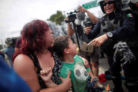 A Honduran migrant, part of a caravan trying to reach the U.S., protects her child as a federal police reacts after migrants stormed the Guatemalan checkpoint to enter Mexico, in Ciudad Hidalgo, Mexico October 19, 2018. REUTERS/Ueslei Marcelino