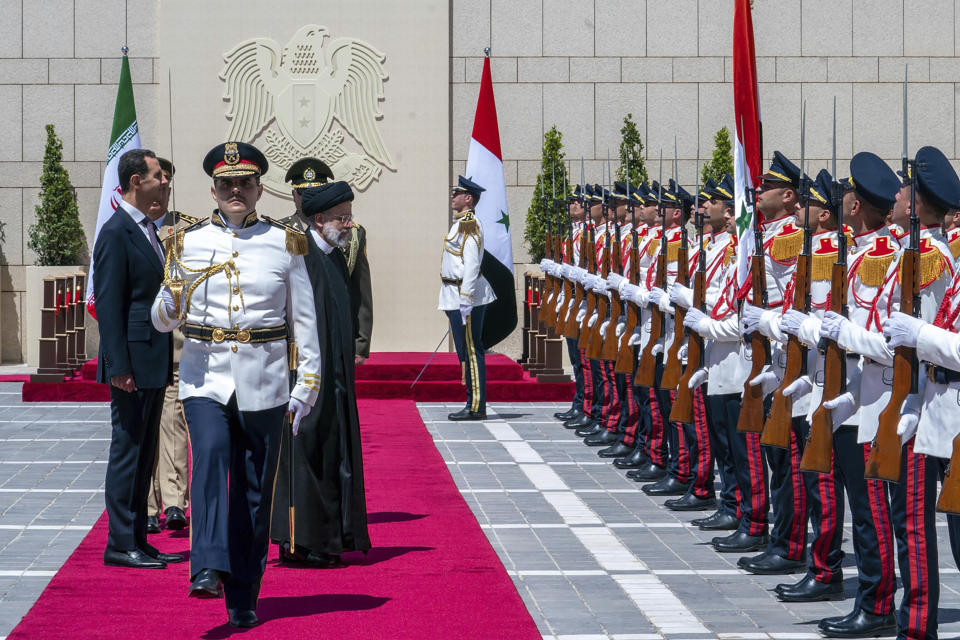 In this photo released by the official Facebook page of the Syrian Presidency, Syrian President Bashar Assad and Iranian President Ebrahim Raisi review an honor guard during a welcome ceremony upon Raisi's arrival in Damascus, Syria, Wednesday, May 3, 2023. (Syrian Presidency via Facebook via AP)