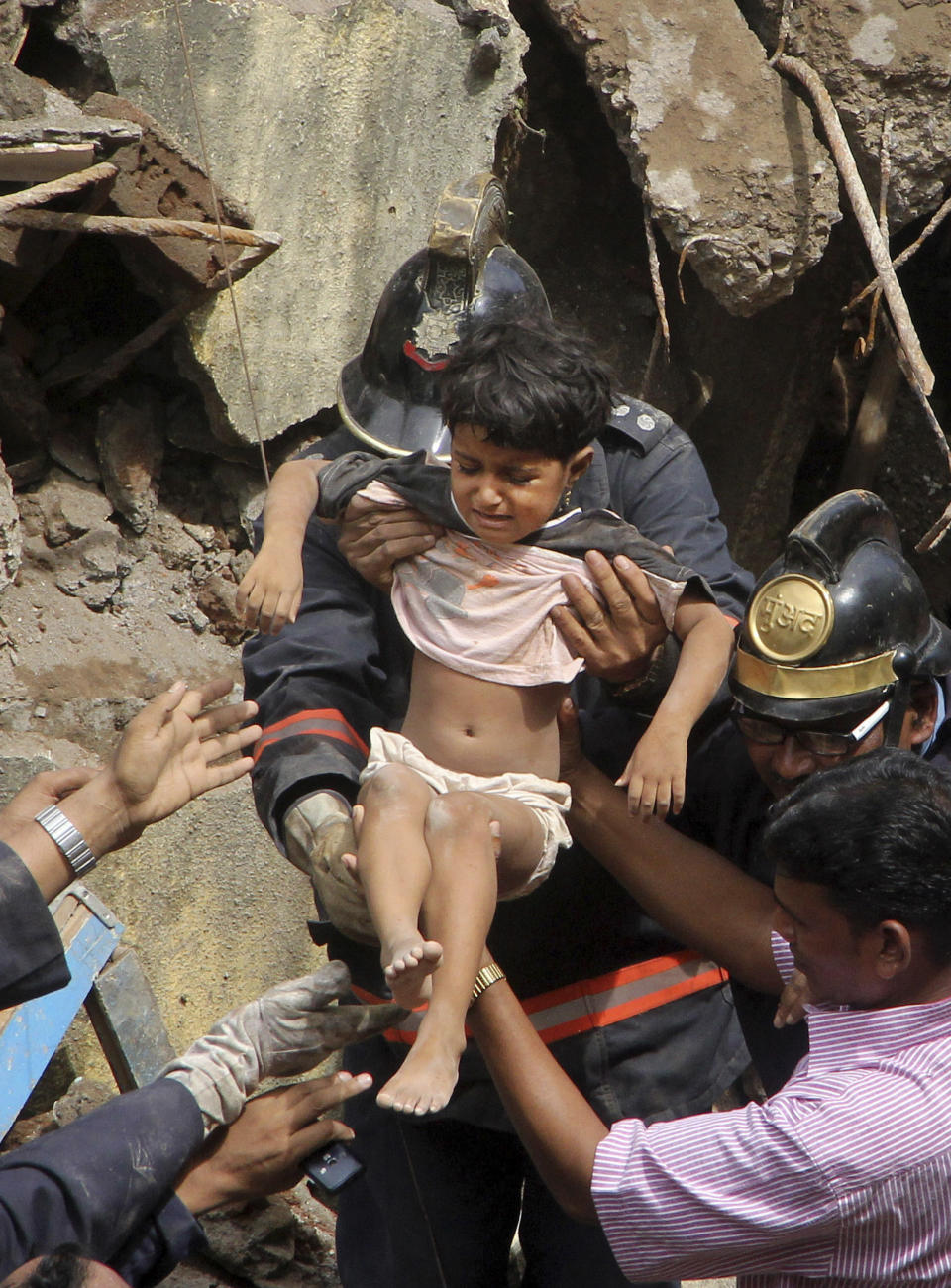 Indian Fire officials rescue a girl from the debris of a collapsed building in Mumbai, India, Friday, Sept. 27, 2013. The multi-story residential building collapsed in India's financial capital of Mumbai early Friday, killing at least three people and sending rescuers racing to reach dozens of people feared trapped in the rubble. (AP)