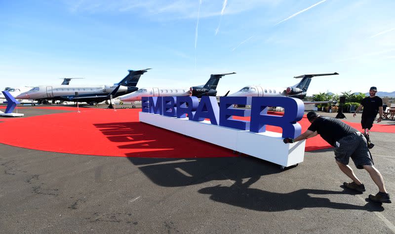 Workers set up at the Embraer booth prior to the opening of the National Business Aviation Association (NBAA) exhibition in Las Vegas