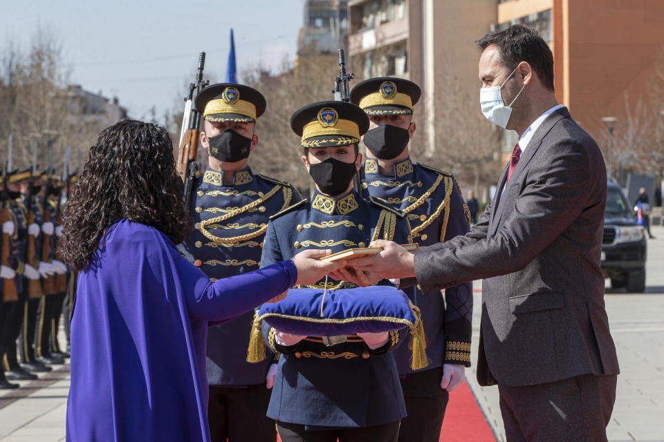 Speaker of parliament Glauk Konjufca, right, symbolically hands over the Kosovo constitution to Kosovo newly elected president Vjosa Osmani-Sadriu, during a presidential hand over ceremony in capital Pristina, Kosovo, on Tuesday, April 6, 2021. 38-year old Osmani took over the presidency after being elected to the post during a two-day extraordinary session of parliament. (AP Photo/ Visar Kryeziu)