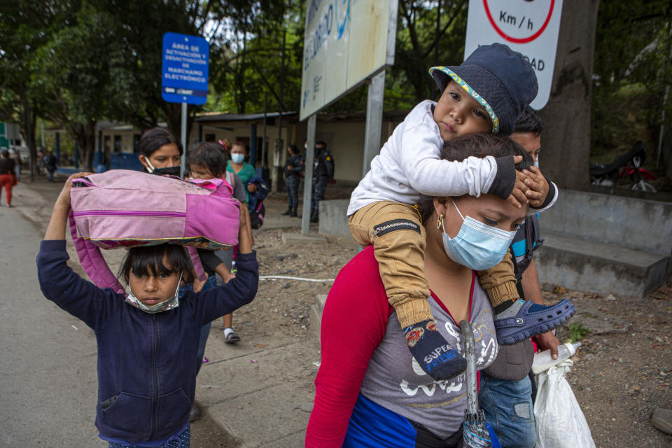 Honduran migrants walk to the border crossing after being transported in an army truck to El Florido, Guatemala, a border point between Guatemala and Honduras, Tuesday, Jan. 19, 2021. A once large caravan of Honduran migrants that pushed its way into Guatemala last week had dissipated by Tuesday in the face of Guatemalan security forces. (AP Photo/Oliver de Ros)