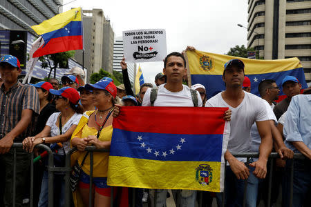 Demonstrators hold Venezuelan flags and a sign reads: ' All the food for all the people! No more dictatorship ' while rallying against Venezuela's President Nicolas Maduro in Caracas, Venezuela May 1, 2017. REUTERS/Carlos Garcia Rawlins