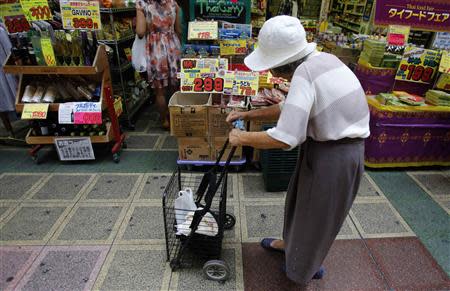 A woman pushing a cart looks at items at a local shopping street in Tokyo in this August 12, 2013 file photo. Japan's top two financial ministers openly disagreed on whether a corporate tax cut was needed to cushion any pain from an increase in the sales tax, as the government upgraded its view of the economy on September 13, 2013 for the seventh time this year. REUTERS/Yuya Shino/Files