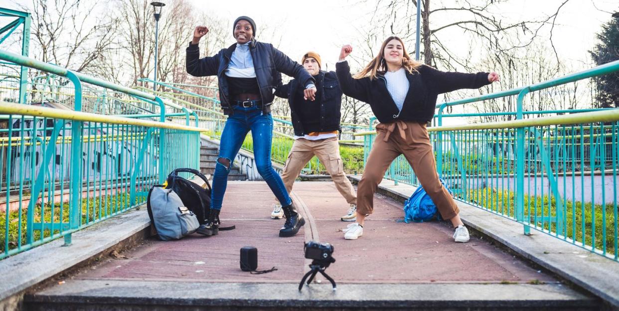 camera set up on tripod in front of three young people dancing