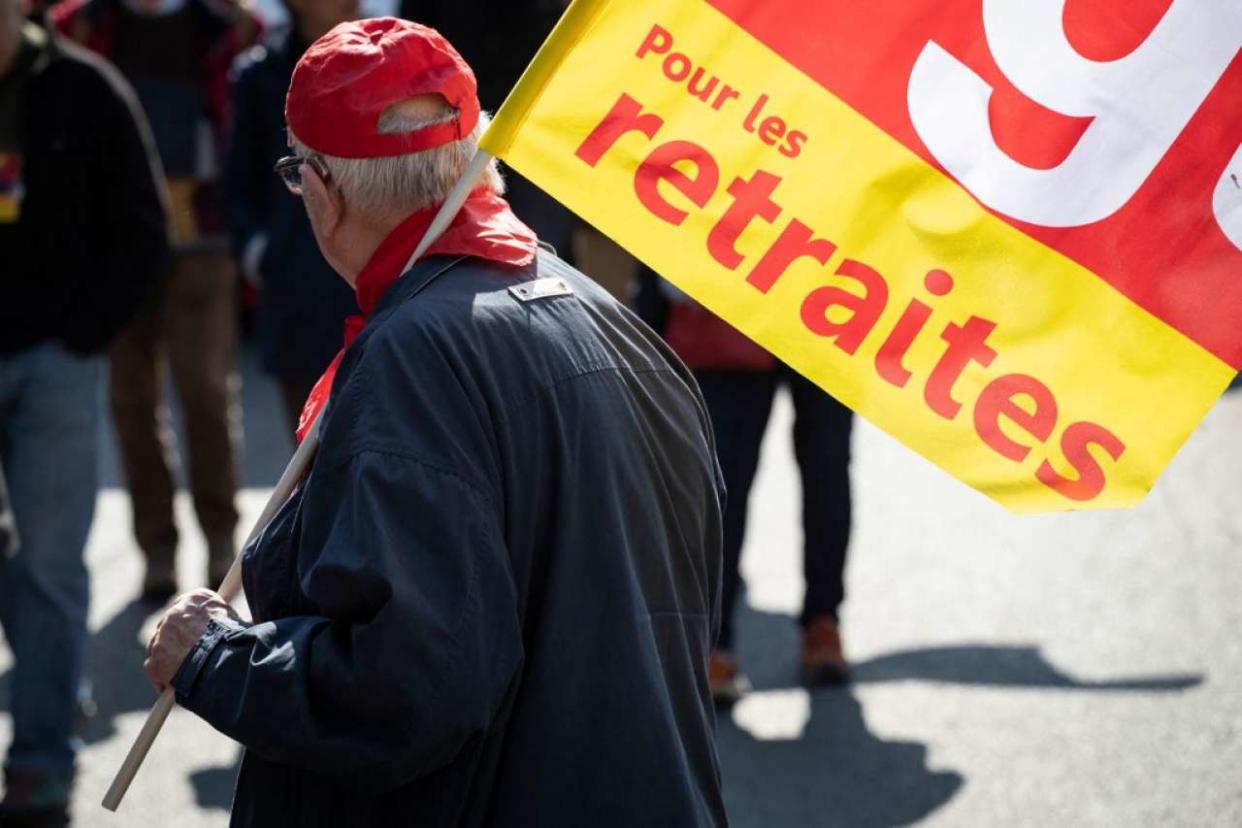 (FILES) In this file photo taken on April 11, 2019 A man waves a French workers' union CGT flag during a march in Paris, as part of a countrywide day of demonstration called by nine retired people unions and organisations to protest against the government policy and for pensions revaluation. - Retirement age, special schemes, employment of seniors, long careers and hardship... the pension reform is highly contested even before its presentation on January 10, 2023. (Photo by Thomas SAMSON / AFP)