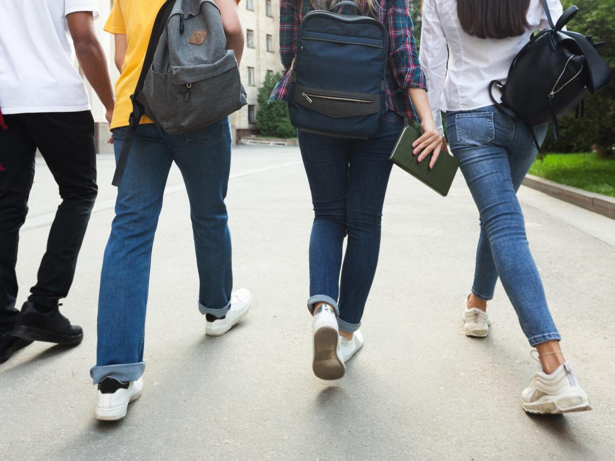 Unrecognizable teenage students in high school campus walking at break