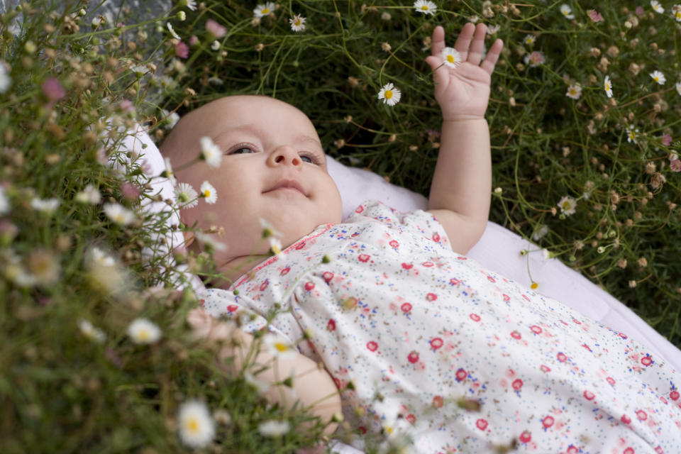 A baby lying in a bed of daisies