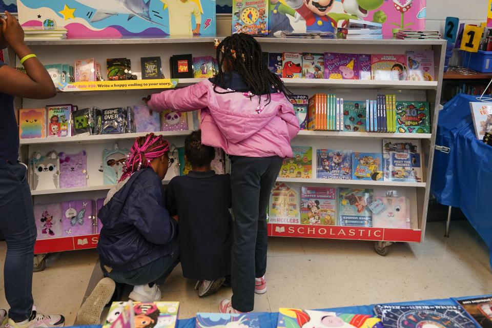 Students look at books during a book fair at Schaumburg Elementary, part of the ReNEW charter network, in New Orleans, Wednesday, April 19, 2023. Mississippi, Alabama and Louisiana have seen a promising turnaround in their student reading scores after passing a series of similar literacy reforms. (AP Photo/Gerald Herbert)