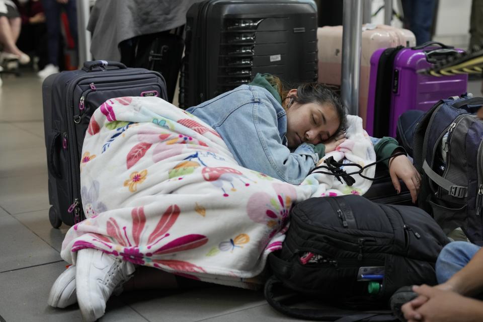 Una pasajera de Viva Air duerme junto a sus maletas luego de que la aerolínea de bajo costo suspendiera sus operaciones en el Aeropuerto Internacional El Dorado de Bogotá, Colombia, el martes 28 de febrero de 2023. (AP Foto/Fernando Vergara)