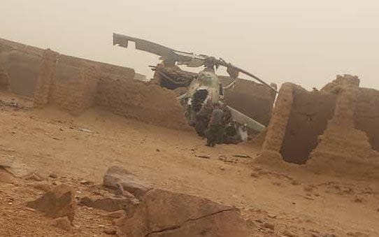 The wreckage of a helicopter lies in between the ruins of mud houses