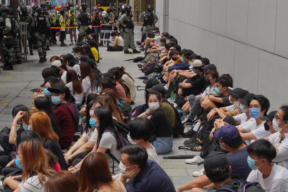 Anti-government protesters sit on ground after being arrested by police in the Causeway Bay district of Hong Kong, Wednesday, May 27, 2020. Hong Kong police massed outside the legislature complex Wednesday, ahead of debate on a bill that would criminalize abuse of the Chinese national anthem in the semi-autonomous city. (AP Photo/Vincent Yu)