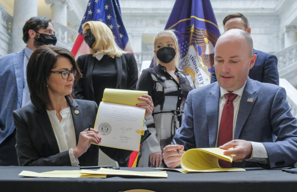 Utah Gov. Spencer Cox Cox, right and Lt. Gov. Deidre Henderson, left, were joined by activists and supporters of SB127 in the Capitol rotunda in Salt Lake City, Tuesday, April 6, 2021 for the ceremonial bill signing that will bring more oversight to the state's so-called troubled-teen industry. Rear from left, state Sen. Mike McKell, R-Spanish Fork, activist Jeff Netto, activist Paris Hilton, activist Caroline Lorson and Rep. Brady Brammer, R-Highland, look on. (Leah Hogsten/The Salt Lake Tribune via AP)