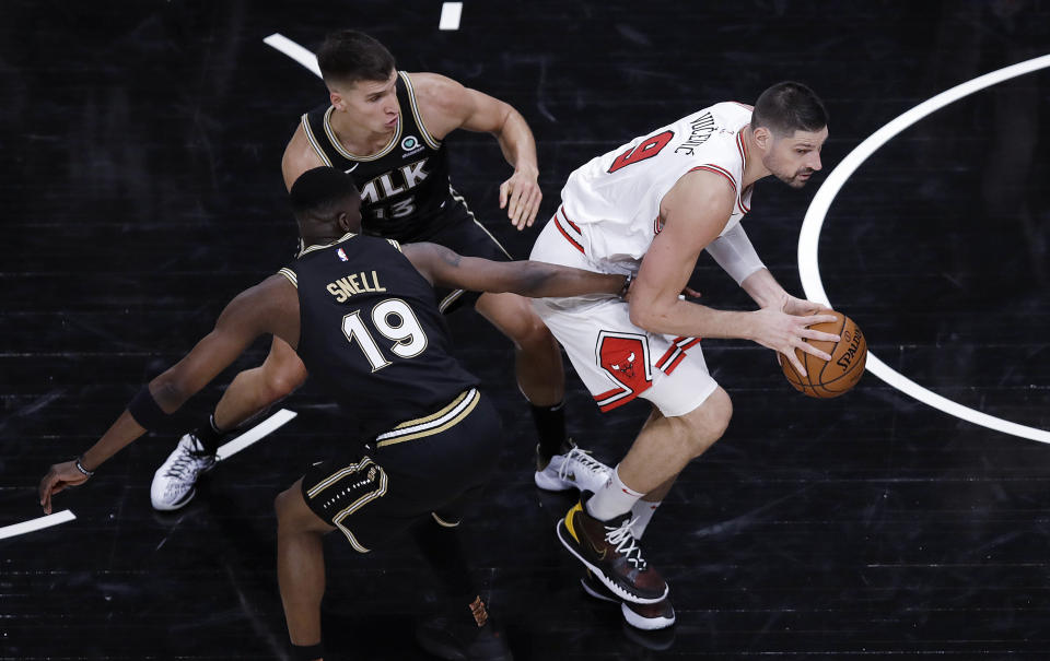 Chicago Bulls' Nikola Vucevic, right, drives the ball away from Atlanta Hawks' Tony Snell (19) and Bogdan Bogdanovic (13) during the second half of an NBA basketball game Friday, April 9, 2021, in Atlanta. (AP Photo/Ben Margot)