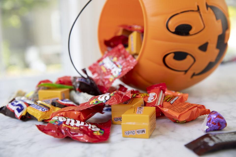 Halloween candy coming out of a pumpkin trick-or-treat bag