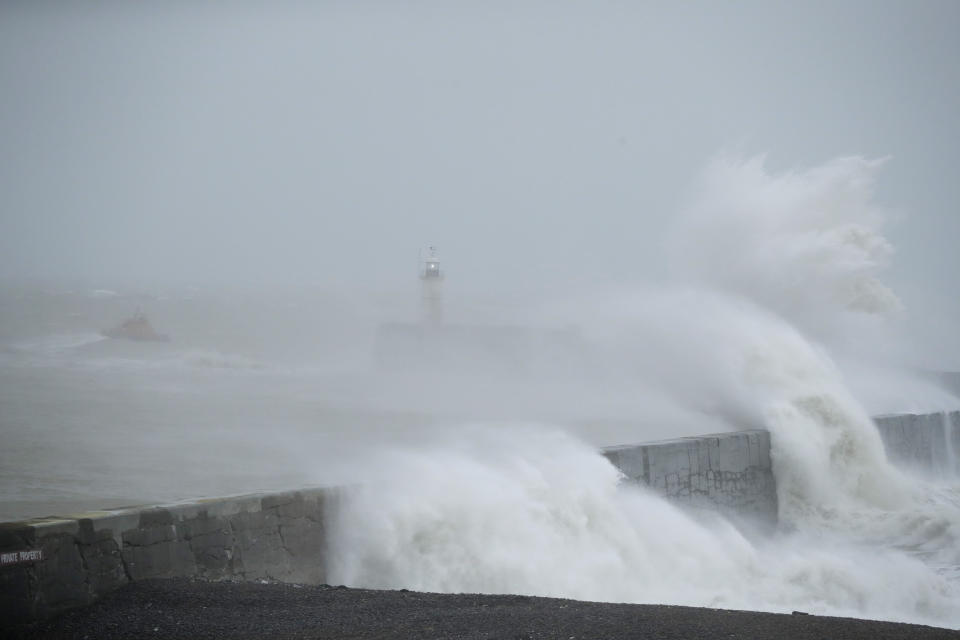 Waves crash over the harbour wall by a lighthouse as a lifeboat passes by at left, as Storm Ciara hits Newhaven, on the south coast of England, Sunday, Feb. 9, 2020. Trains, flights and ferries have been cancelled and weather warnings issued across the United Kingdom and in northern Europe as the storm with winds expected to reach hurricane levels batters the region. (AP Photo/Matt Dunham)