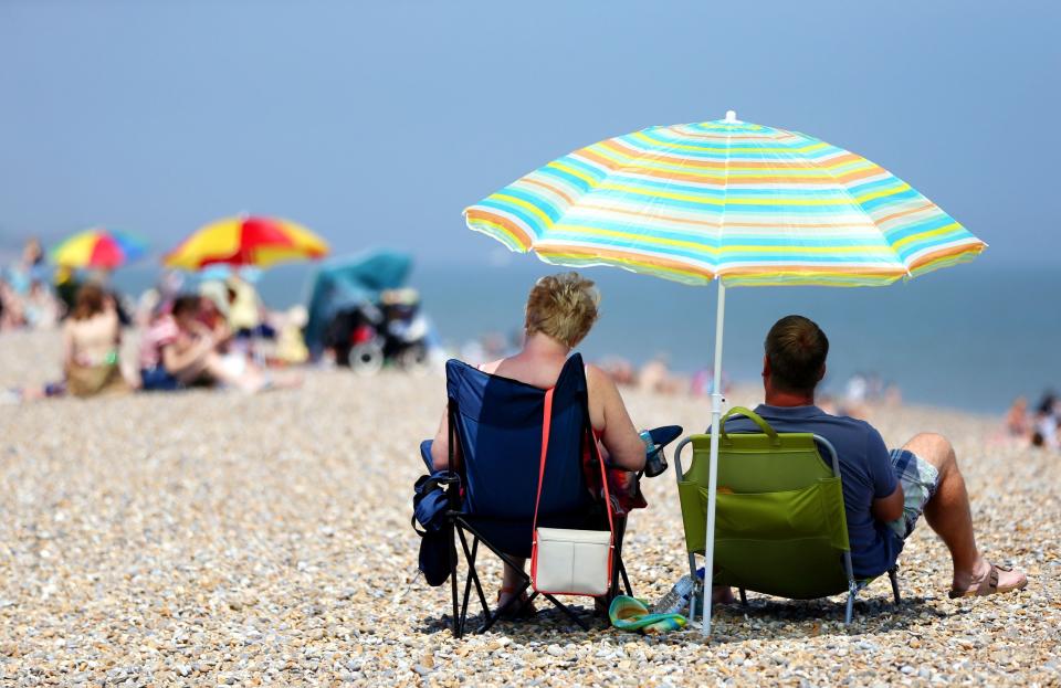 Sunbathers shelter under beach umbrellas on the seafront in Aldeburgh, Suffolk, as Britain has basked in the hottest day of the year so far, with temperatures expected to soar as the heatwave continues into next week.