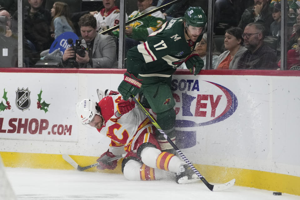 Calgary Flames defenseman Rasmus Andersson (4) and Minnesota Wild left wing Marcus Foligno (17) collide while following the puck during the first period of an NHL hockey game Thursday, Dec. 14, 2023, in St. Paul, Minn. (AP Photo/Abbie Parr)