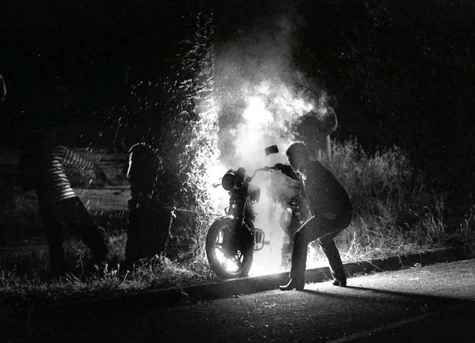 Members of the crowd surround a motorcycle set ablaze by rioters just off Foothill and California boulevards before midnight Saturday April 28, 1990.