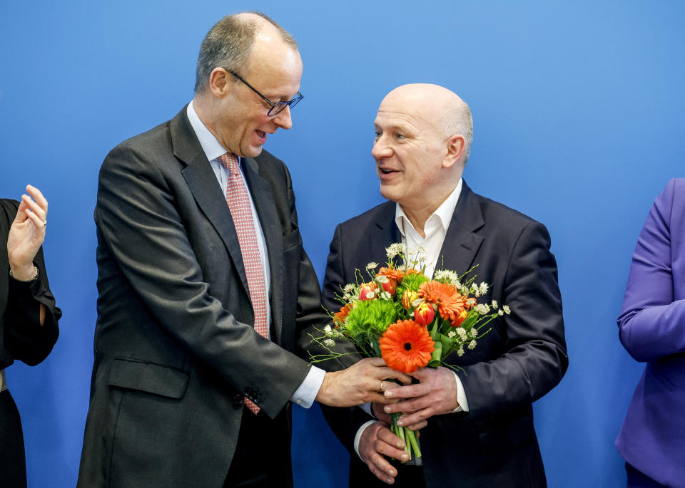 Friedrich Merz, left, chairman of the German Christian Democratic party (CDU) hands over a bunch of flowers to the party's top candidate for the Berlin state elections, Kai Wegner, right, during a party's executive committee meeting in Berlin, Germany, Monday, Feb 13, 2023. Germany’s conservative Christian Democrats on Monday celebrated their victory in a Berlin state election re-run made necessary by serious voting glitches in 2021. The party said the result shows it can appeal to voters in urban areas with center-right policies that include tough talk on immigration. (Axel Heimken/dpa via AP)