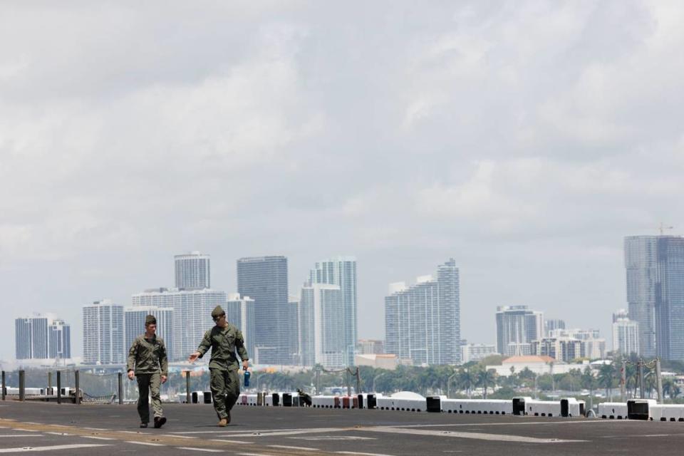 Two members of a heavy marine helicopter squadron walk across the flight deck of the USS Bataan in front of the Miami skyline during the opening day of Fleet Week on Monday, May 6, 2024, at Norwegian Cruise Lines Terminal in PortMiami. Alie Skowronski/askowronski@miamiherald.com