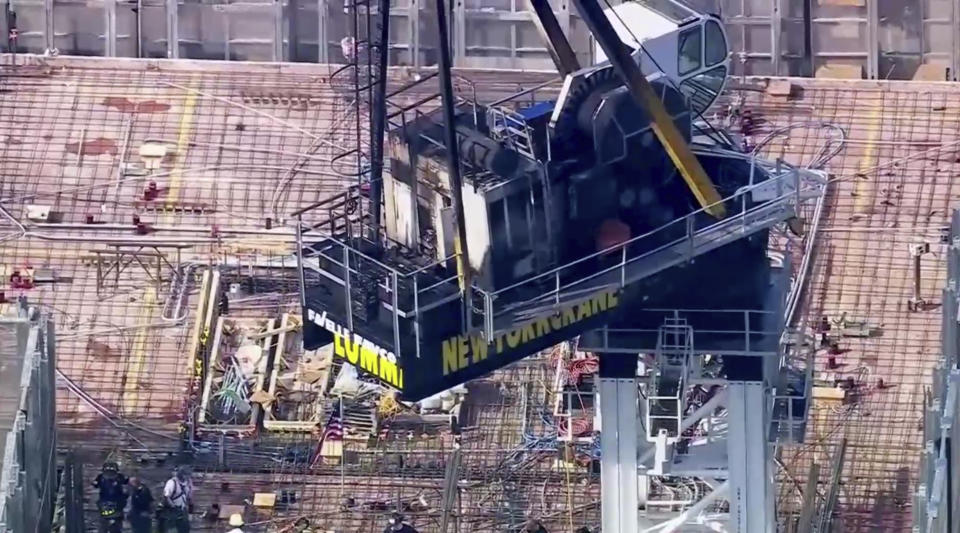 Emergency responders are on the scene after a large construction crane caught fire in Manhattan on Wednesday, July 26, 2023 in New York. The crane caught fire and its arm hit a building as it crashed to the street below. (WABC via AP)